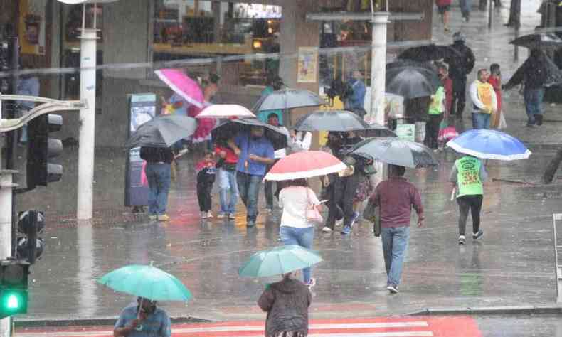 Pessoas na chuva com sombrinhas e guarda-chuvas