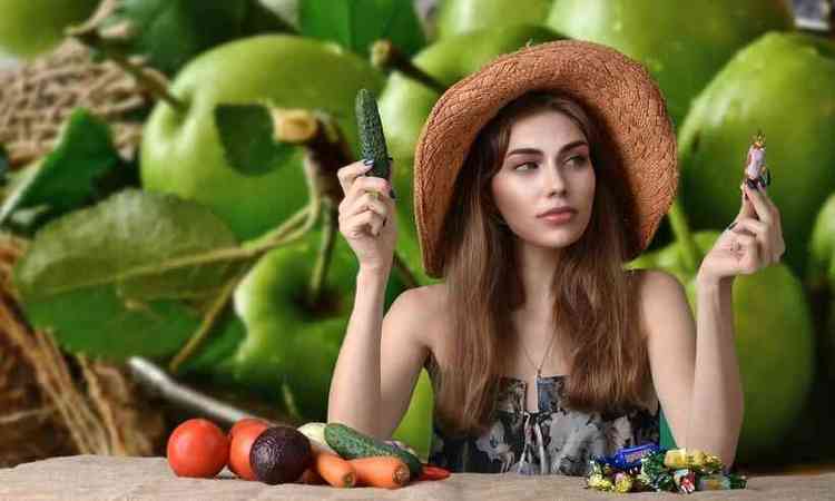 moa de chapu, olha para uma mesa que tem um monte de balas, doces e outro de legumes e frutas