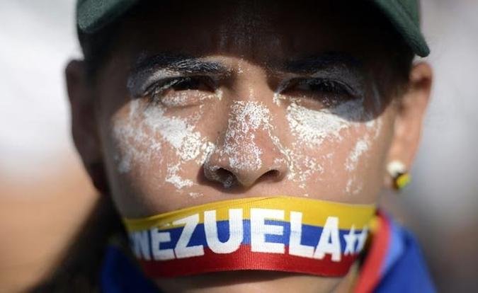 Manifestante usa faixa com bandeira da Venezuela como morda�a em protesto contra a persegui��o � liberdade de imprensa liderada pelo presidente Maduro(foto: LEO RAMIREZ/AFP)