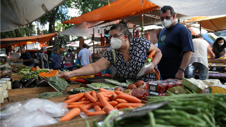 Mulher escolhendo legumes em feira livre