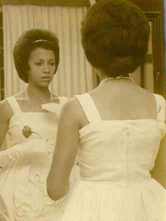 Debutante est em frente ao espelho, de luvas e segurando uma rosa, no baile promovido no Clube dos Oficiais, nos anos 1960