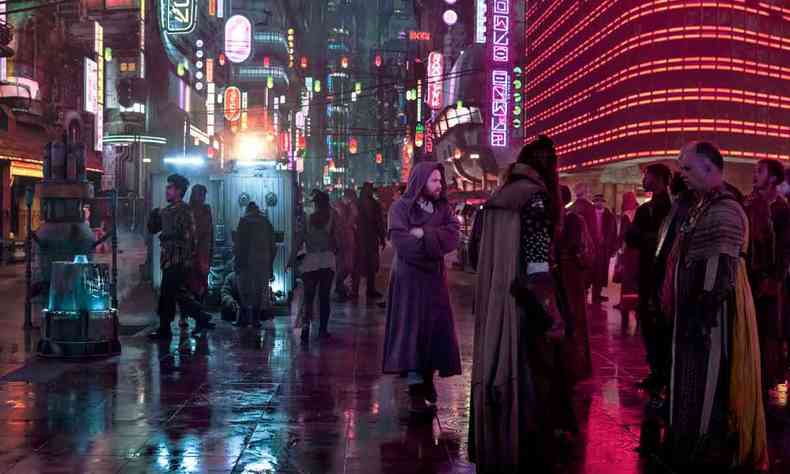 Ator usando longa capa e capuz, no cenário futurista e noturno de Obi-Wan Kenobi 