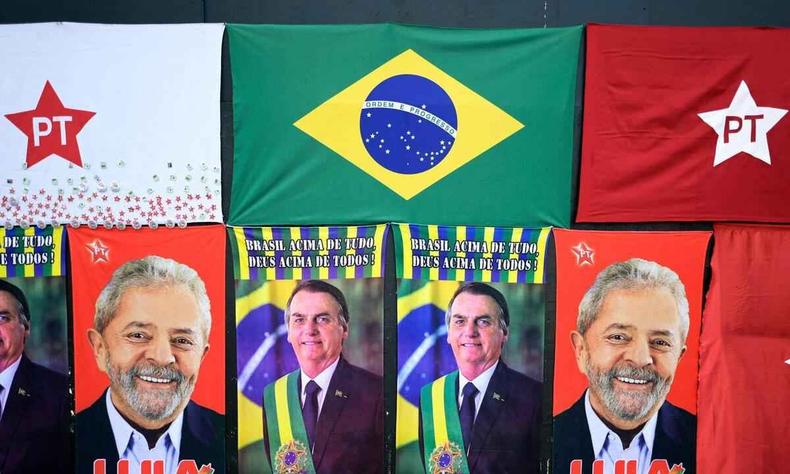 Bandeiras do PT e do Brasil e toalhas de banho estampadas com Lula e Bolsonaro expostas e um painel preto de uma loja no centro de BH
