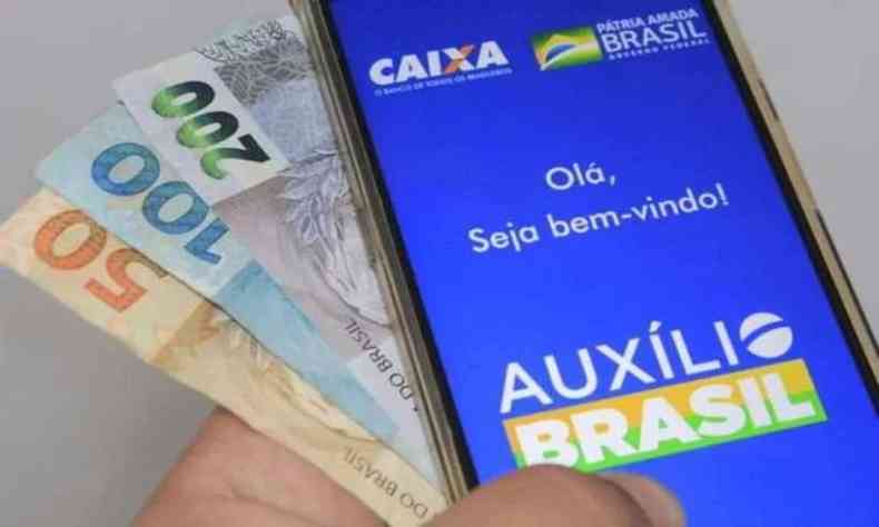 Dinheiro e telefone aberto na pgina do auxlio brasil 
