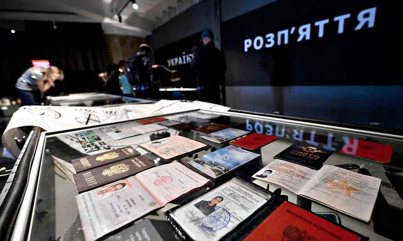 No museu, pessoas observam vitrine onde esto expostos passaportes e anotaes de soldados russos mortos no confronto com a Ucrnia