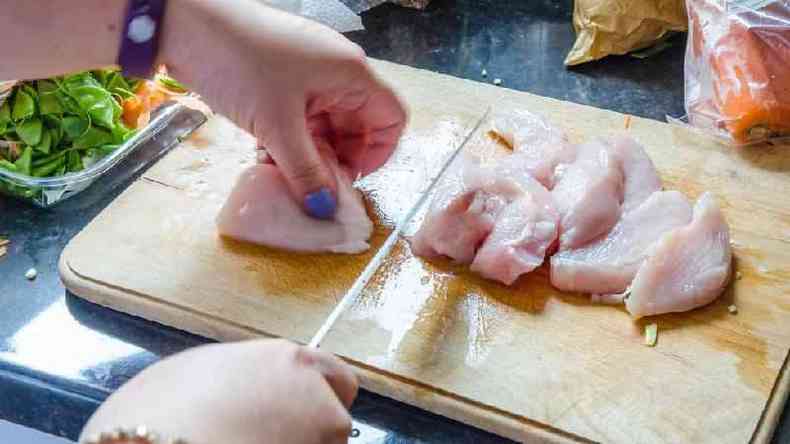 Mulher cortando frango em tbua de carne