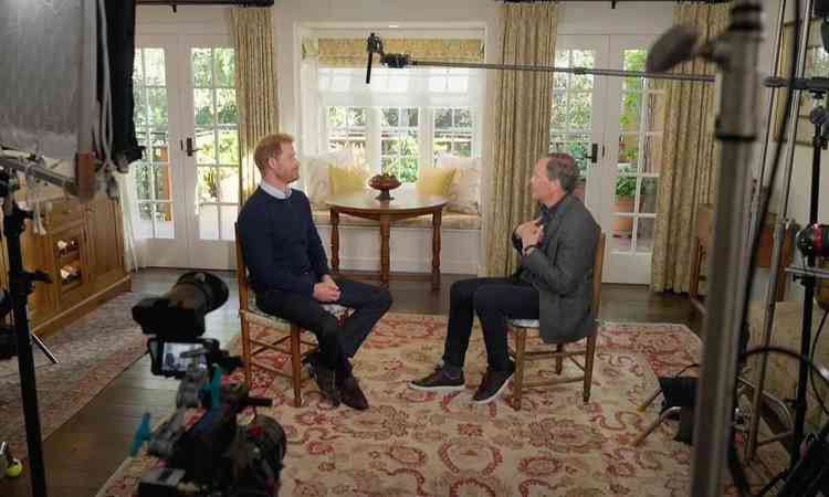 Prncipe Harry d entrevista ao apresentador britnico Tom Bradby numa sala residencial, com decorao sbria e jardim ao fundo