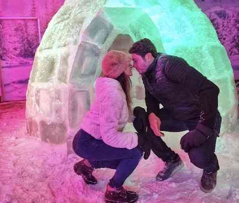 Casal se beijando em frente uma escultura de gelo