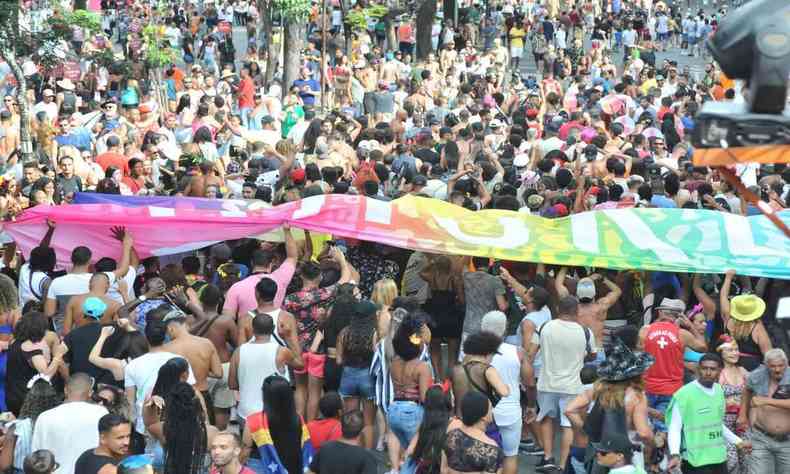 Uma multido de pessoas no carnaval de belo Horizonte. Uma grande bandeira colorida est sendo aberta meio deles