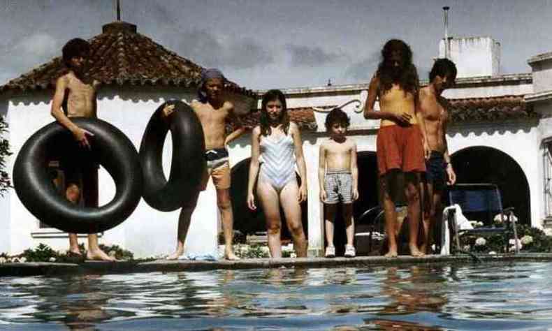 Jovens em trajes de banho segurando boias  beira de uma piscina, em cena de 'o pntano' 