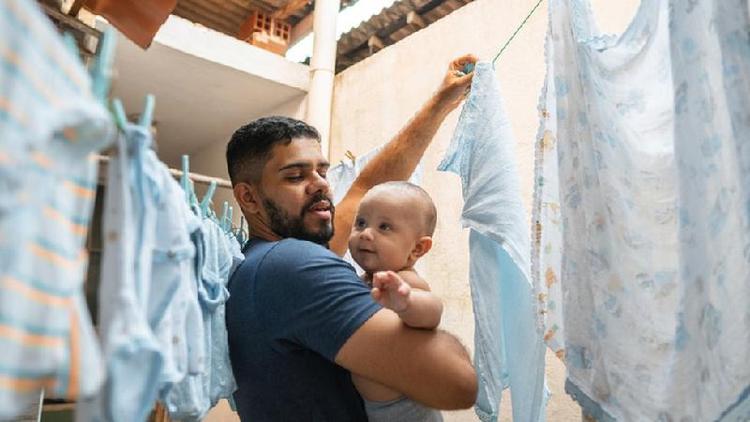Pai lavando roupa e cuidando de beb