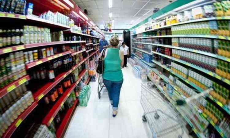 mulher, de costas, andando em um corredor de supermercado