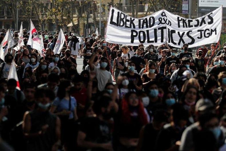 Manifestantes seguram cartaz com linguagem neutra em protesto no Chile (foto: AFP) Pessoas carregam faixa em manifestação com o texto 'Libertad a lxs presxs políticxs'