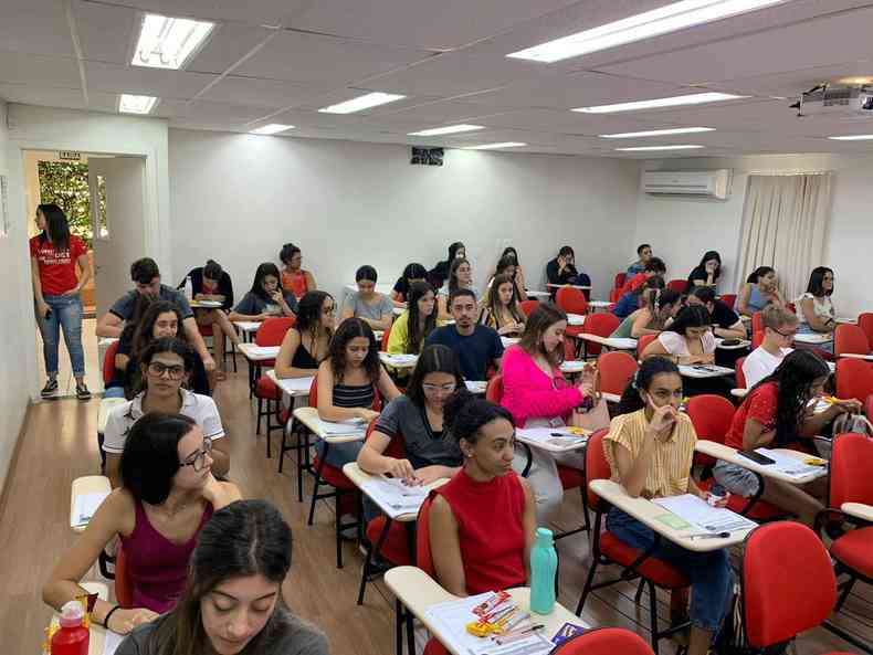 Sala cheia de alunos fazendo prova