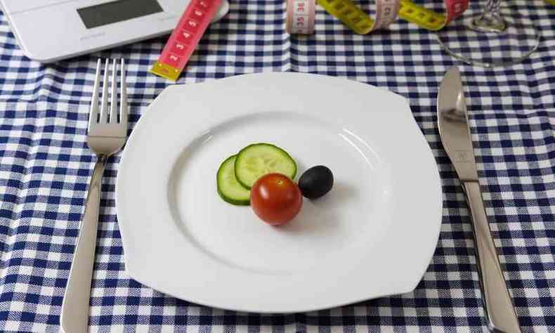 prato com tomate e pepino e, ao lado, uma fita mtrica e uma balana