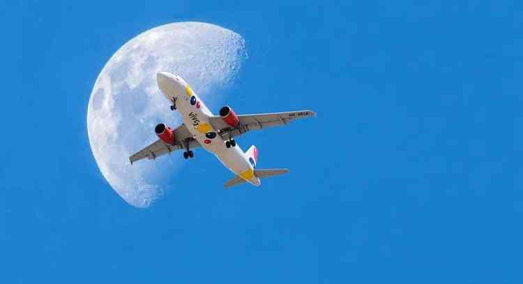 avião em subida passa sob a lua