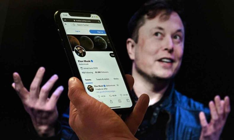 Elon Musk, em primeiro plano um telefone celular