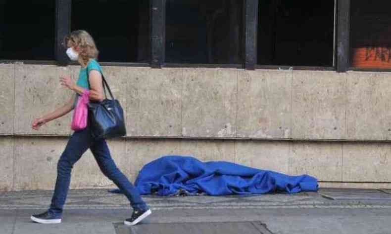 Imagem de morador de rua deitado com uma coberta