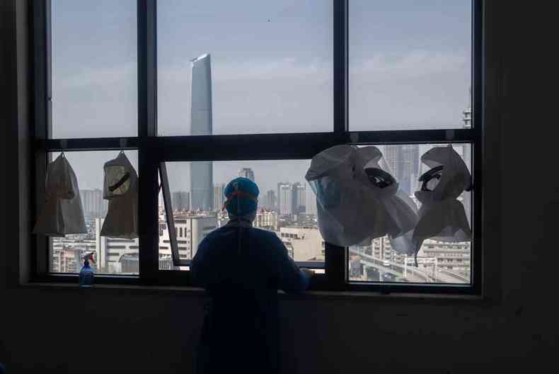 Um profissional de sade em uma janela de um hospital em Wuhan, na China(foto: STR / AFP)