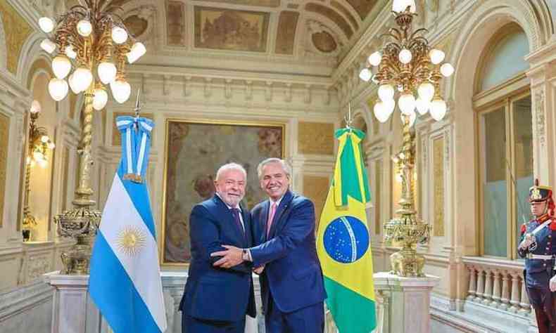 Lula e Fernandez se abraam entre as bandeiras da Argentina e do Brasil