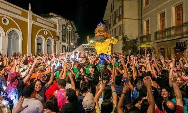 Boneco gigante em meio a uma multido de folies e casares histricos