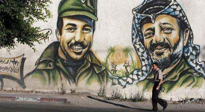 Homem palestino caminha em frente � grafite com a imagem de Arafat. Equipe de especialistas su��os j� chegou � Cisjord�nia(foto: AFP PHOTO/MOHAMMED ABED )