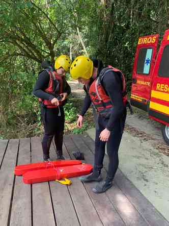 Dois bombeiros vestidos com roupara de mergulho para buscas em rio 