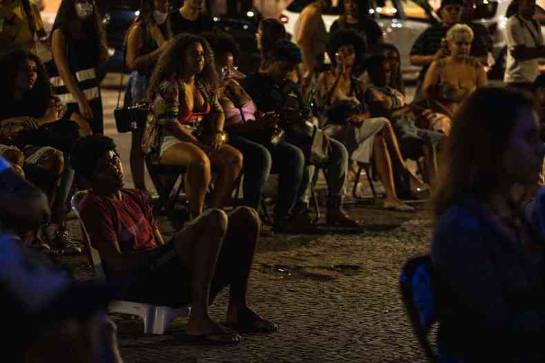 Pessoas atentas, sentadas no cho, assistem filme na Rua Aaro Reis, em BH