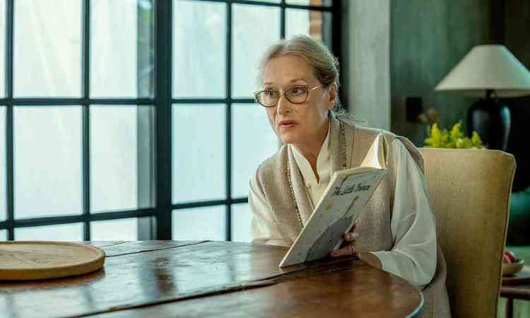 Meryl Streep sentada  mesa mostra o exemplar do livro O Pequeno Prncipe
