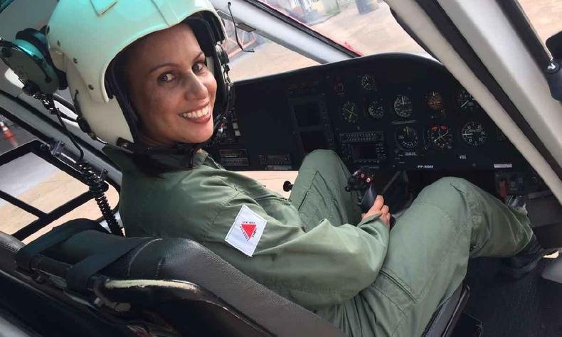 Coronel Daniela Lopes dentro de um helic�ptero com farda do corpo de bombeiros e capacete branco