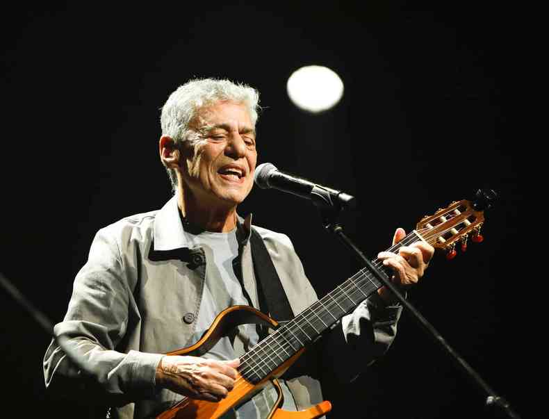 Chico Buarque no palco, cantando e tocando violo