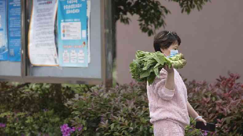 Uma mulher caminha com um punhado de verduras em uma rea residencial em 22 de abril de 2022 em Xanga