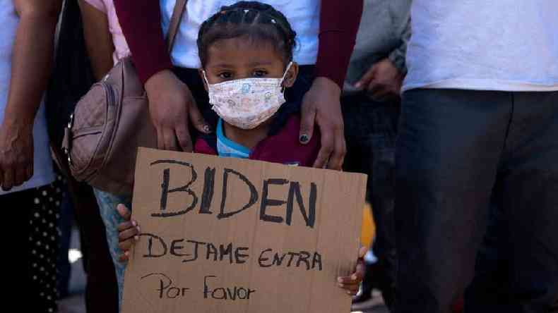 Criana pede em placa que Biden a deixe entrar nos EUA, em um protesto de migrantes na fronteira do Mxico com a Califrnia