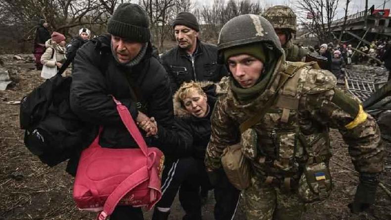 Uma mulher visivelmente exausta  assistida ao atravessar uma ponte destruda na cidade de Irpin, a noroeste de Kiev