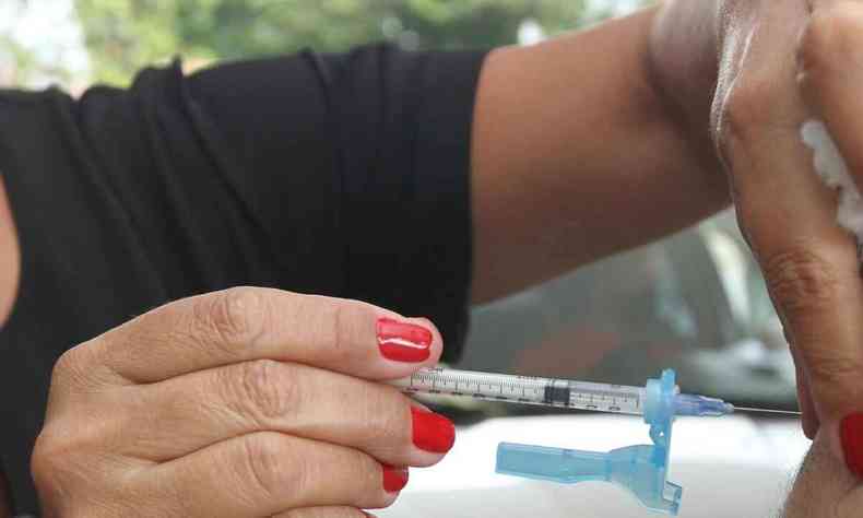 Enfermeira com seringa contendo a vacina Pfizer, aplicando nos pacientes
