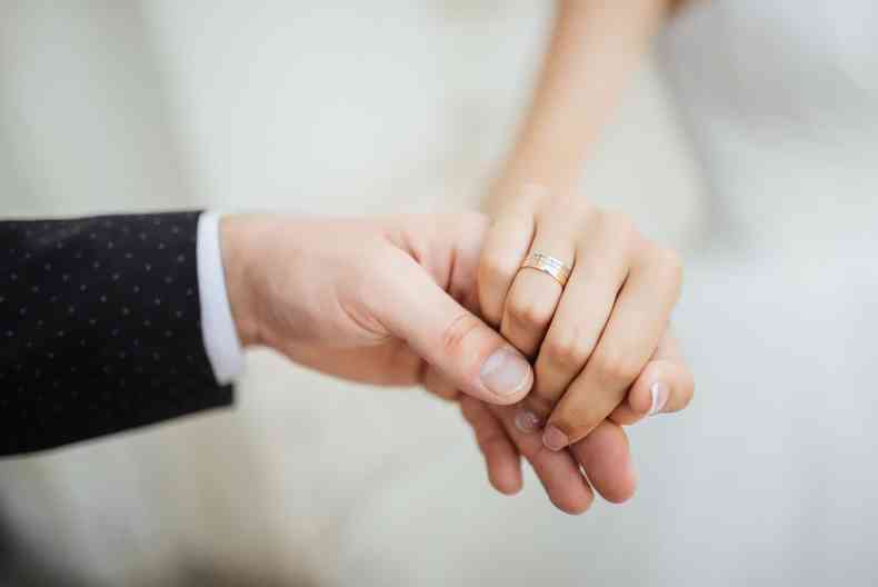 mãos dadas de um noivo e sua noiva 