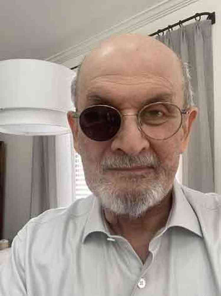 De palet preto e camisa cinza, Salman Rushdie olha para a cmera