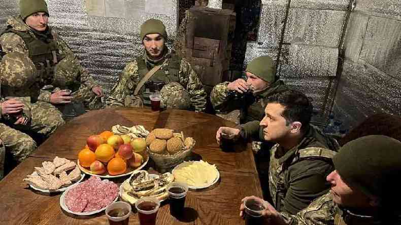 Soldados ucranianos recebem a visita do presidente na frente oriental da Ucrnia ao redor de uma mesa
