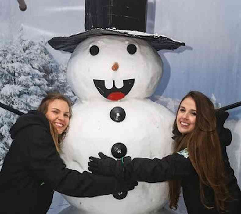 Amigas abraçando um boneco de neve