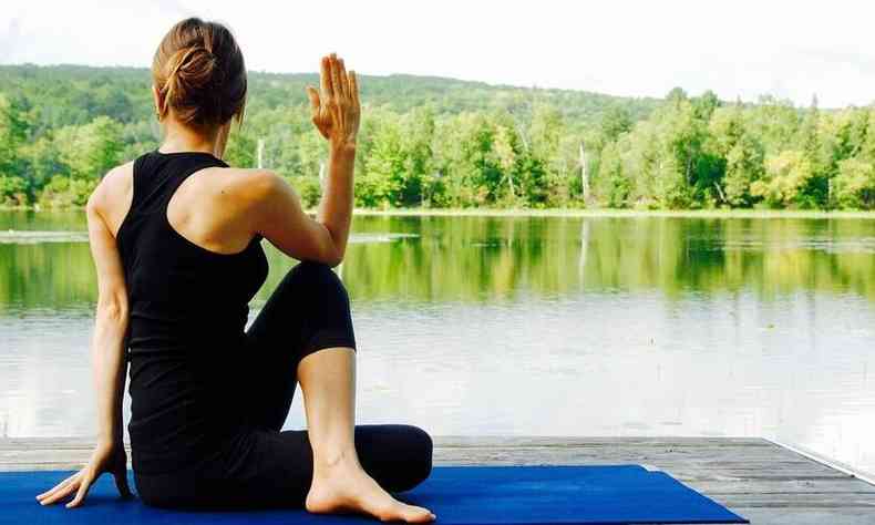 mulher em um posio de ioga em frente a um lago