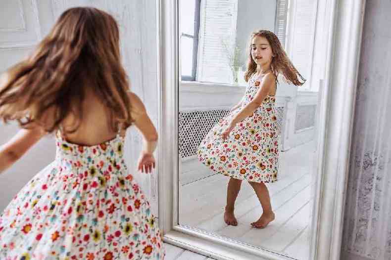 Menina de vestido em frente a espelho