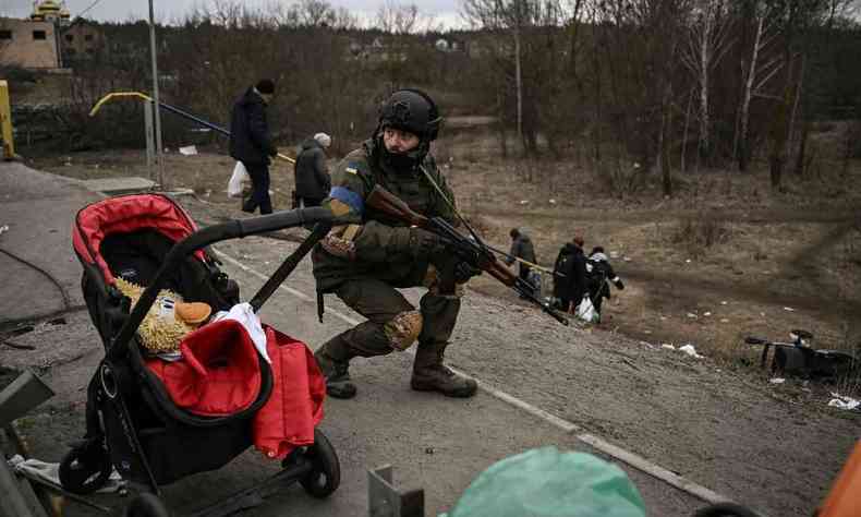 Soldado ucraniano se protege enquanto as pessoas evacuam a cidade de Irpin em 13 de maro de 2022
