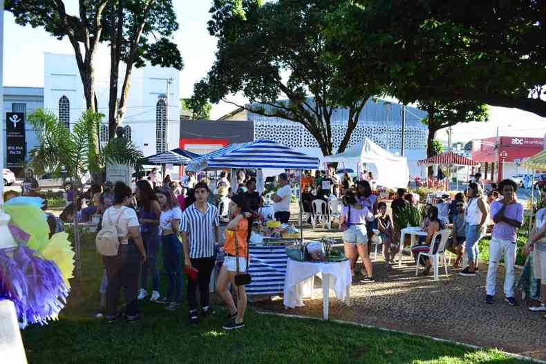 Barracas espalhadas pela praa e pessoas transitando pelo local.