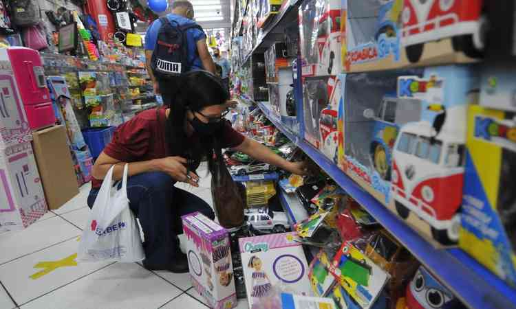 mulher escolhendo brinquedo na prateleira para comprar 