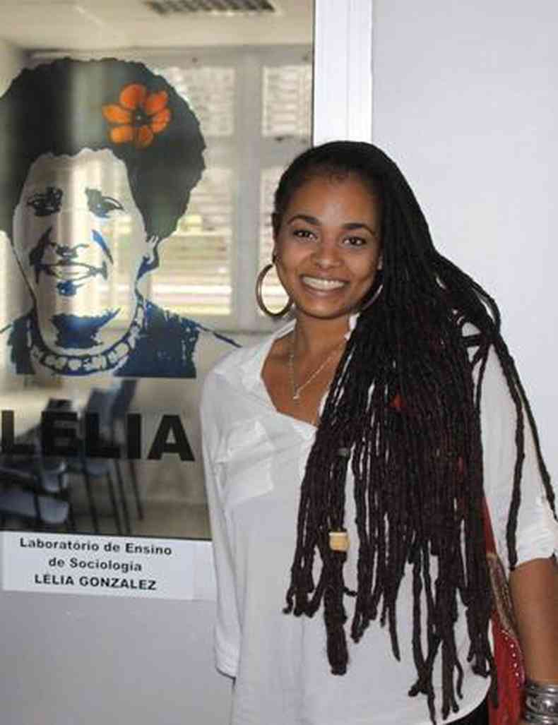 Melina de Lima em frente a cartaz com imagem da avó Lélia Gonzalez