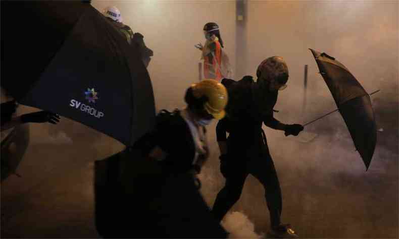 Manifestantes correm aps a polcia disparar gs lacrimogneo para dispers-los na marcha contra uma polmica lei de extradio em Hong Kong (foto: Vivek Prakash / AFP)