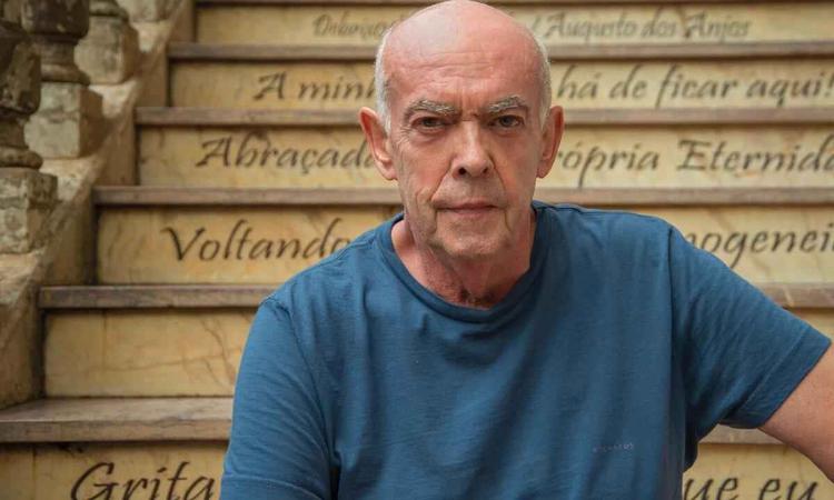 O cineasta Helvcio Ratton olha para a cmera, sentado em uma escada
