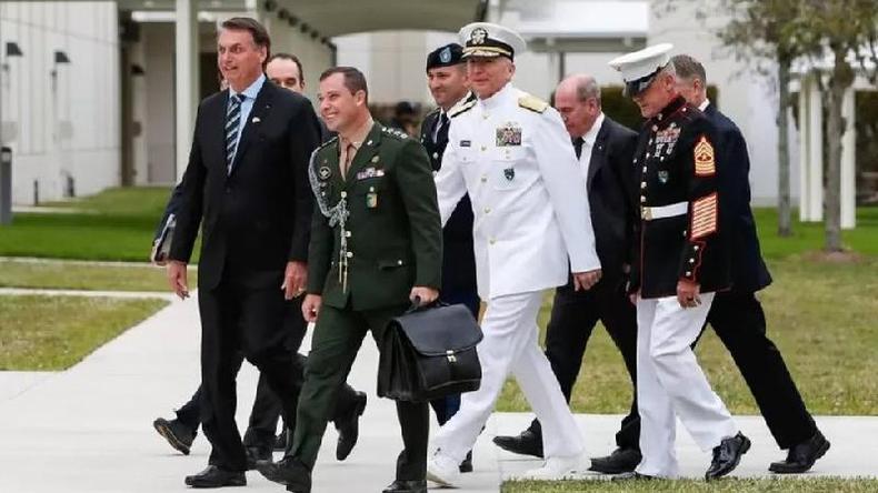 Mauro Cid (ao centro, de uniforme verde escuro) era um dos assessores mais próximos de Bolsonaro e é militar da ativa(foto: Presidência da República) Homens idosos e um jovem, alguns de uniforme militar, caminham ao lado de Bolsonaro