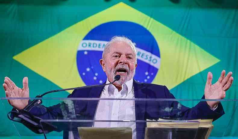 Lula  frente de uma bandeira do Brasil