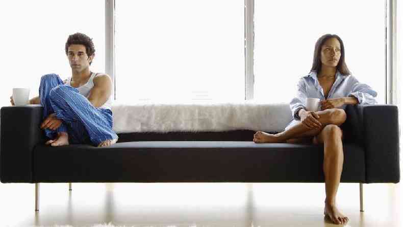 Casal sentado em um sofá com feições tristes